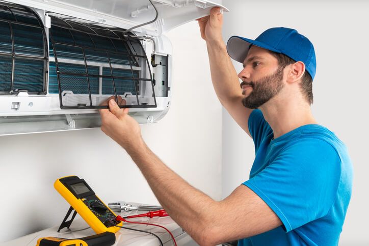 HVAC Specialist repairing a ductless heating and cooling ventilation system unit inside a client's home.