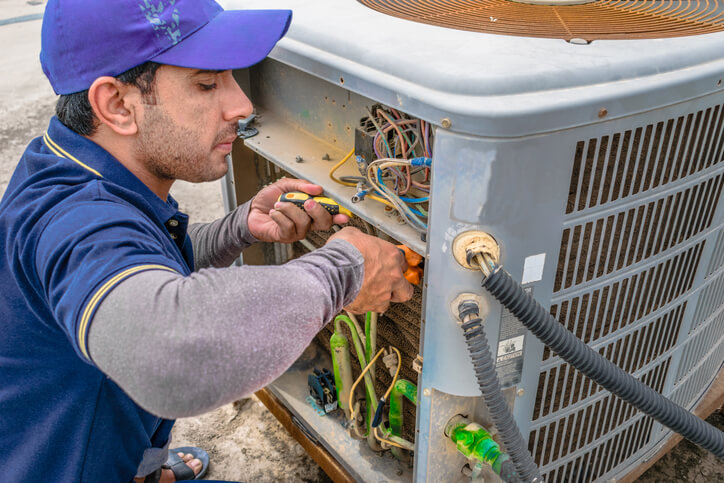 HVAC Specialist repairing the central air conditioner compressor.