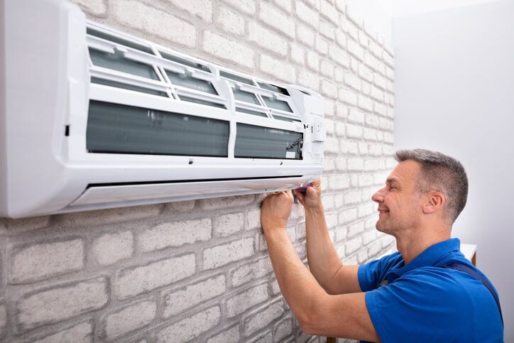 HVAC Specialist installing a ductless heating and cooling ventilation system unit inside a client's home.