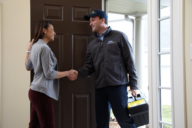 HVAC Specialist making a house call for heating repair, shaking hands with the client upon entering the home.