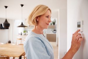 Woman adjusting a digital thermostat