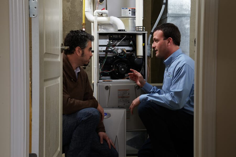 HVAC specialist consults with customer about his heating system in his home.