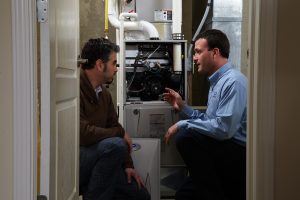 Technician and customer looking inside a furnace