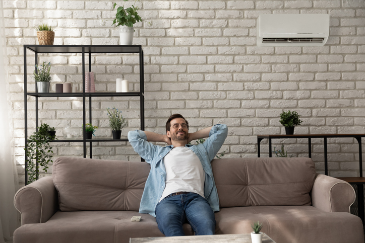 man enjoying his ductless mini-split system in his home, living room area