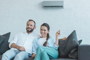a couple sits together on a sofa underneath a ductless system